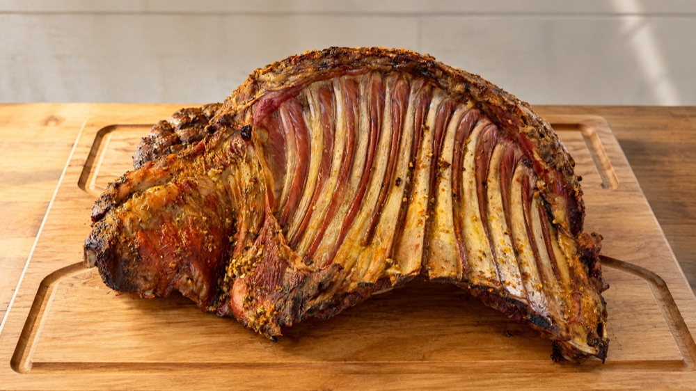 Costillar de cordero con lomo asado entero sobre tabla de madera