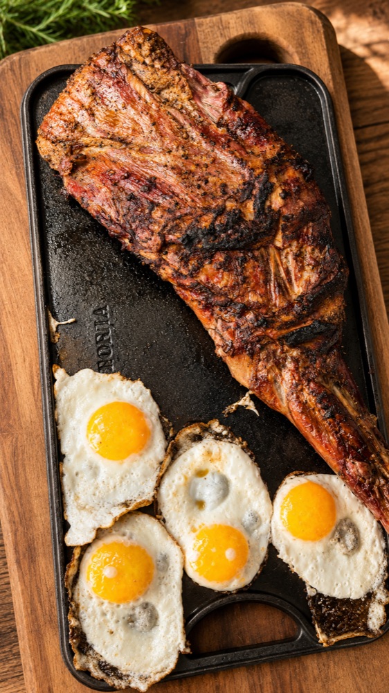 Paleta de cordero a la parrilla servida en plancha con huevos fritos